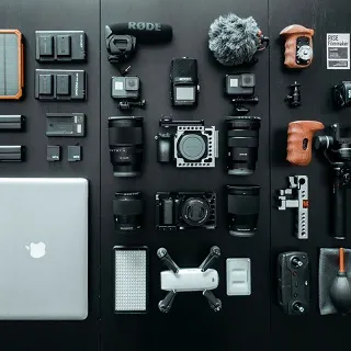 Matériel de vlog comme drone, caméras sportives, SSD portable, appareil photo mis sur une table.